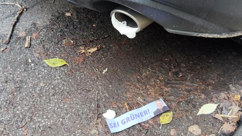 "Russland-gesteuerte Akteure" sollen vermeintlich versuchen Wahl zu manipulieren In einem Auspuff hängt Bauschaum, davor liegt ein Sticker mit dem Gesicht von Robert Habeck auf der Straße