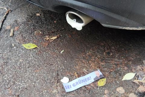 In einem Auspuff hängt Bauschaum, davor liegt ein Sticker mit dem Gesicht von Robert Habeck auf der Straße