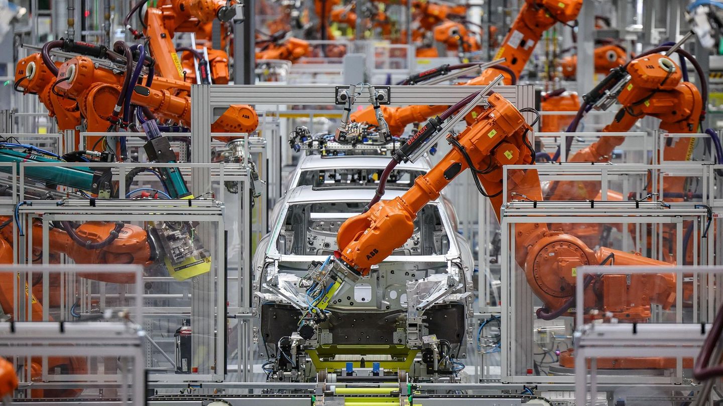 Industrieroboter arbeiten an der Karosserie für einen vollelektrischen Porsche Macan im Werk Leipzig