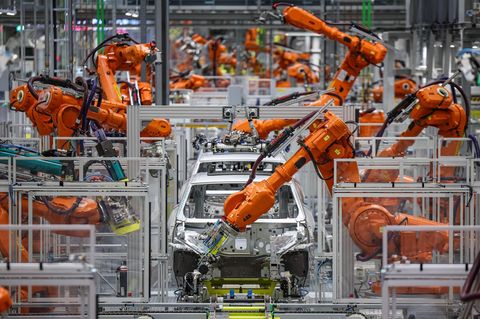 Industrieroboter arbeiten an der Karosserie für einen vollelektrischen Porsche Macan im Werk Leipzig