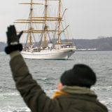 Eine Frau winkt beim Auslaufen der "Gorch Fock"