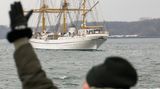Eine Frau winkt beim Auslaufen der "Gorch Fock"