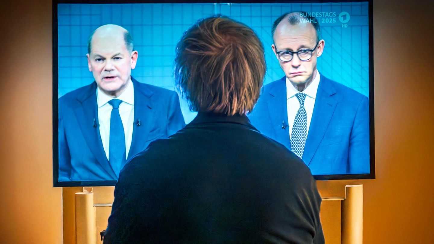 Eine Person schaut auf einem Fernseher das TV-Duell zwischen Scholz und Merz