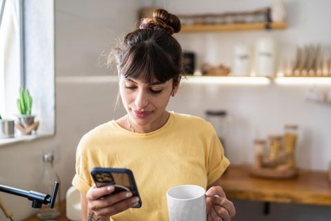 Eine Frau schaut in der Küche auf ihr iPhone
