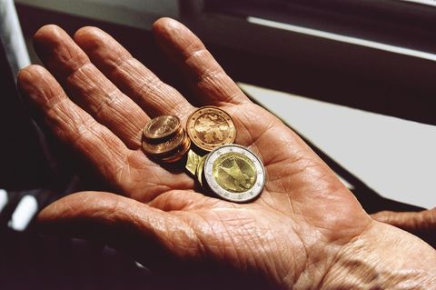 Euromünzen in der Hand einer Rentnerin