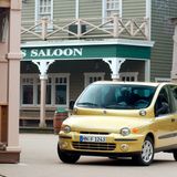 Ein gelber Fiat Multipla vor einem Saloon