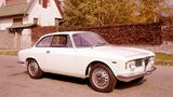 Ein weißer Alfa Romeo Giulia parkt vor einem Gartenzaun