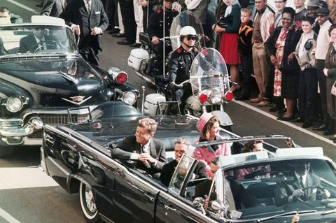 John F. Kennedy (l.) und Ehefrau Jackie bei der verhängnisvollen Fahrt durch Dallas im Jahr 1963