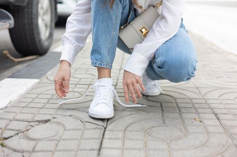 The girl's feet are in new white sneakers and jeans.