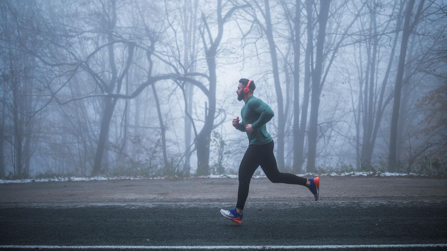Joggen und Feinstaub: Junger Mann läuft durch den Nebel im Winter Joggen und Feinstaub: Junger Mann läuft durch den Nebel im Winter