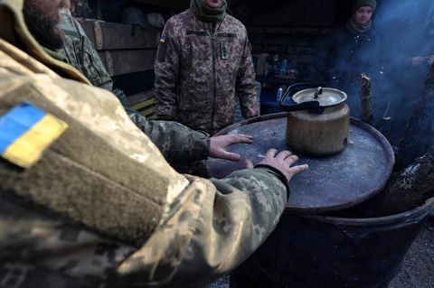 Ukrainische Soldaten wärmen sich an einem Kessel