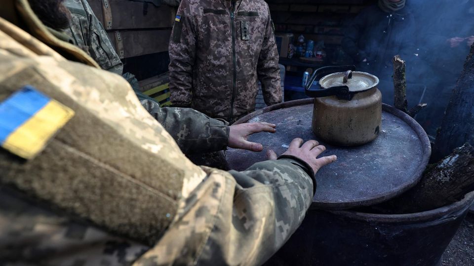 Ukrainische Soldaten wärmen sich an einem Kessel