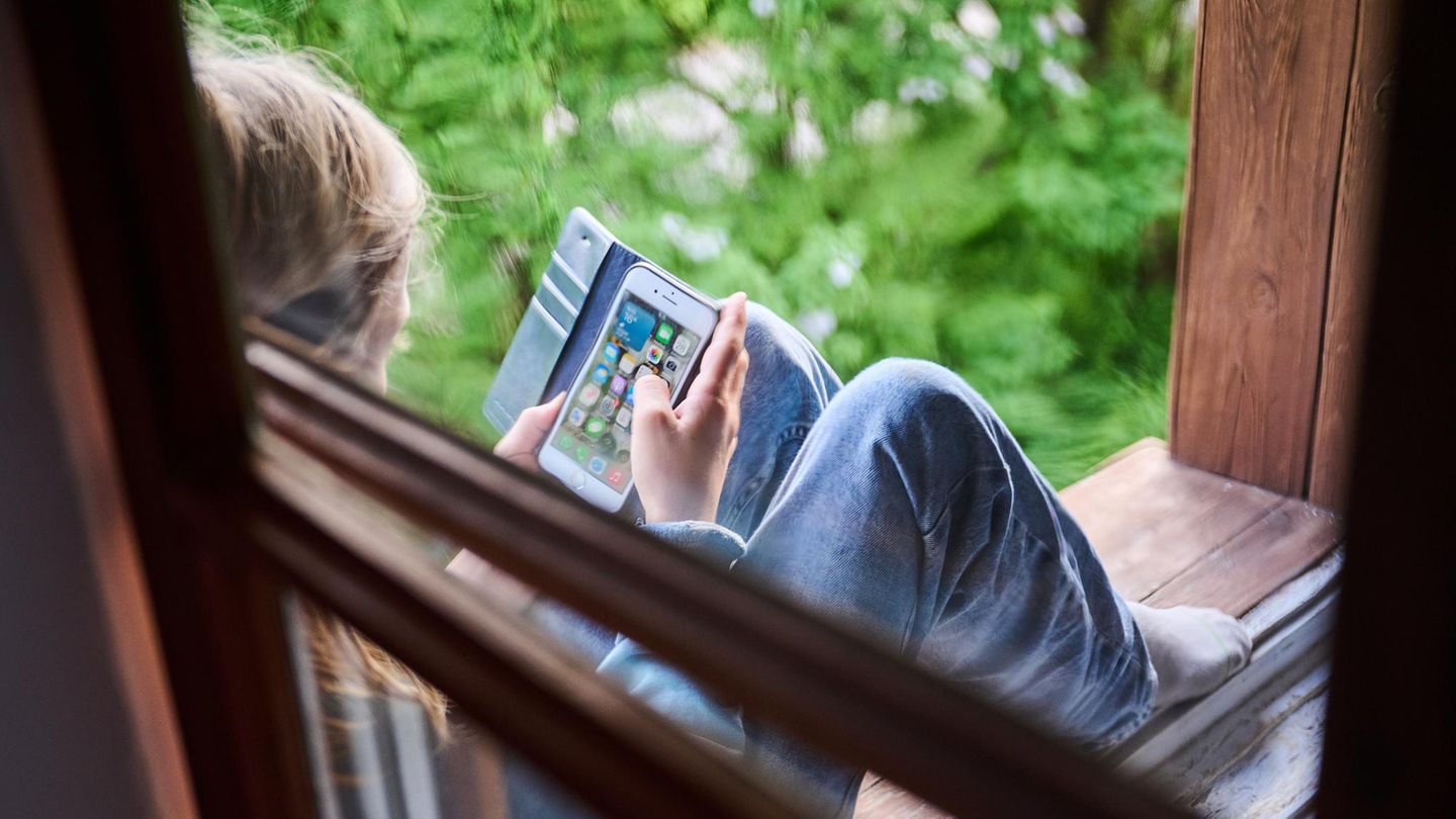 Tiktok: Junge sitzt am Fenster mit Handy in der Hand