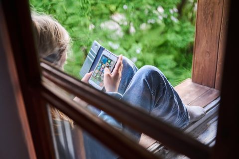 Tiktok: Junge sitzt am Fenster mit Handy in der Hand