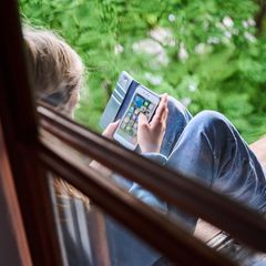 Tiktok: Junge sitzt am Fenster mit Handy in der Hand