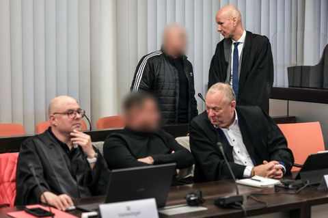 Zwei Angeklagte im Schumacher-Prozess sprechen im Gerichtssaal mit ihren Verteidigern