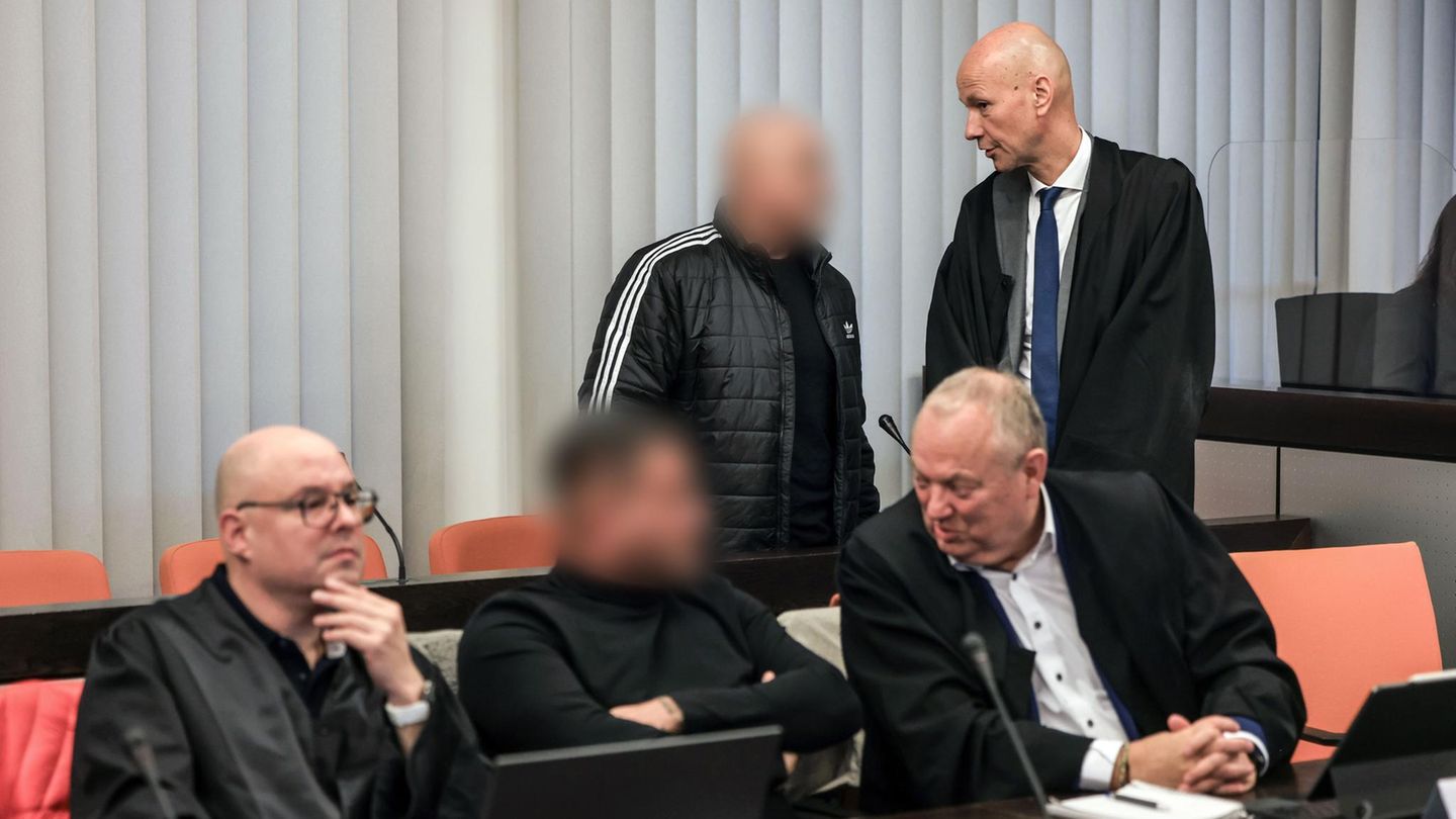 Zwei Angeklagte im Schumacher-Prozess sprechen im Gerichtssaal mit ihren Verteidigern