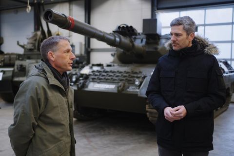 Ingo Zamperoni steht vor einem Panzer und spricht mit Ulrich Nothwang, einem Reservisten in olivgrüner Jacke