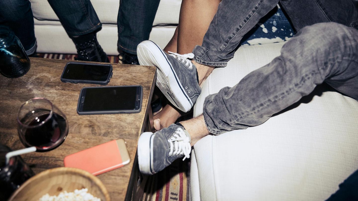 Smartphones liegen auf einem Tisch zwischen einer Freundesgruppe