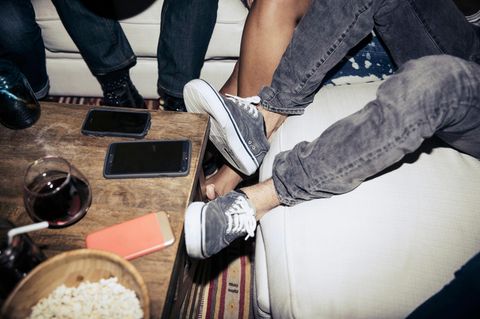 Smartphones liegen auf einem Tisch zwischen einer Freundesgruppe