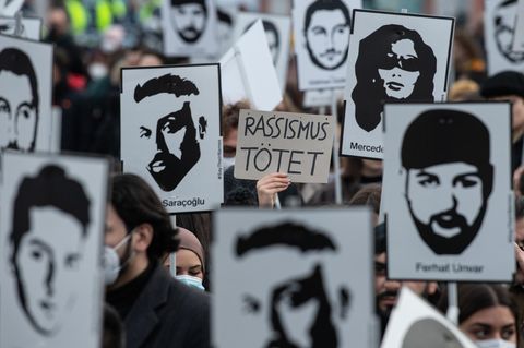 Auf einer Demo werden Schilder mit den Gesichtern der Opfer des Hanau-Attentats hochgehalten
