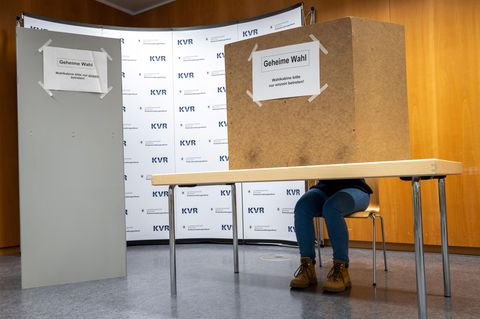 Eine Frau sitzt in einer deutschen Wahlkabine
