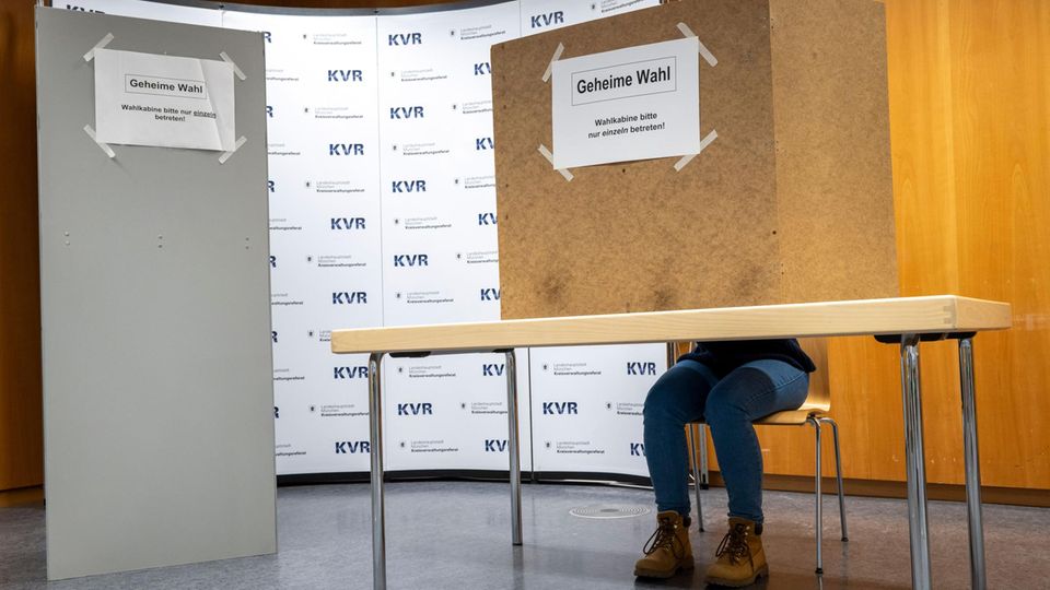Frei, aber auch geheim: Diese Regeln müssen im Wahlraum eingehalten werden Eine Frau sitzt in einer deutschen Wahlkabine