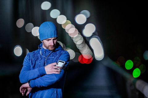 Handyhalter beim Joggen: Junger Läufer tippt auf seinem Smartphone