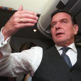 Gerhard Schröder gesitkuliert in einem Flugzeug