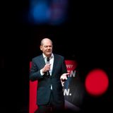 Olaf Scholz hält vor einer schwarzen Wand eine Rede