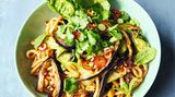 Udon-Nudeln mit gerösteten Auberginen     Für 1 Person  1 Aubergine (250g)   1 Knoblauchzehe   1 Pak Choi   1 EL geröstete ungesalzene Erdnusskerne   1 EL süße Chilisauce  150g Instant-Udon-Nudeln (aus dem Asia-Laden)  4 Frühlingszwiebeln   1⁄2 frische rote Chilischote   1⁄2 Romanasalatherz   2 Stängel Minze oder Koriandergrün  1 EL Crunchy Erdnuss & Sesam- Chiliöl (Knusper-Chiliöl mit Sesam & Erdnussstückchen)  1 EL Balsamico-Essig     Vorbereitung 7 Minuten   Garzeit 20 Minuten   1 Schublade   Die Auberginen der Länge nach in 1cm dicke Scheiben und dann in lange 1 cm breite Streifen schneiden. Den Gitterboden aus der Airfryer-Schublade entfernen, die Auberginenstreifen hineingeben und 15 Minuten bei 200°C garen. Nach der Hälfte der Zeit durchrühren.Den Knoblauch schälen und in feine Scheiben schneiden.Den Pak Choi längs vierteln. Wenn die 15 Minuten vorüber sind, die Schublade herausziehen, den Knoblauch und die Erdnüsse über die Auberginen streuen, die süße Chilisauce über das Gemüse träufeln und durch Rütteln der Schublade gleichmäßig verteilen. Seitlich den Pak Choi einlegen und weitere 5 Minuten bei 200 °C garen, bis die Aubergine weich und sämig ist.In einer Schüssel die Udon-Nudeln mit kochendem Wasser bedecken und quellen lassen. Die Frühlingszwiebeln putzen und in feine Scheiben schneiden, die halbe Chili in Ringe schneiden. Die Salatblätter trennen, die Kräuter abzupfen.Die Nudeln abgießen und mit dem größten Teil der Frühlingszwiebeln und der Chili sowie dem Chiliöl und dem Essig zu dem Gemüse in die Schublade geben. Alles gut vermengen, sorgfältig abschmecken und auf einem Teller anrichten. Die Salatblätter daneben platzieren, alles mit den restlichen Chilis, Frühlingszwiebeln und mit den Kräutern garnieren und servieren.