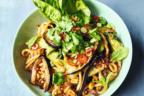 Udon-Nudeln mit gerösteten Auberginen     Für 1 Person  1 Aubergine (250g)   1 Knoblauchzehe   1 Pak Choi   1 EL geröstete ungesalzene Erdnusskerne   1 EL süße Chilisauce  150g Instant-Udon-Nudeln (aus dem Asia-Laden)  4 Frühlingszwiebeln   1⁄2 frische rote Chilischote   1⁄2 Romanasalatherz   2 Stängel Minze oder Koriandergrün  1 EL Crunchy Erdnuss & Sesam- Chiliöl (Knusper-Chiliöl mit Sesam & Erdnussstückchen)  1 EL Balsamico-Essig     Vorbereitung 7 Minuten   Garzeit 20 Minuten   1 Schublade   Die Auberginen der Länge nach in 1cm dicke Scheiben und dann in lange 1 cm breite Streifen schneiden. Den Gitterboden aus der Airfryer-Schublade entfernen, die Auberginenstreifen hineingeben und 15 Minuten bei 200°C garen. Nach der Hälfte der Zeit durchrühren.Den Knoblauch schälen und in feine Scheiben schneiden.Den Pak Choi längs vierteln. Wenn die 15 Minuten vorüber sind, die Schublade herausziehen, den Knoblauch und die Erdnüsse über die Auberginen streuen, die süße Chilisauce über das Gemüse träufeln und durch Rütteln der Schublade gleichmäßig verteilen. Seitlich den Pak Choi einlegen und weitere 5 Minuten bei 200 °C garen, bis die Aubergine weich und sämig ist.In einer Schüssel die Udon-Nudeln mit kochendem Wasser bedecken und quellen lassen. Die Frühlingszwiebeln putzen und in feine Scheiben schneiden, die halbe Chili in Ringe schneiden. Die Salatblätter trennen, die Kräuter abzupfen.Die Nudeln abgießen und mit dem größten Teil der Frühlingszwiebeln und der Chili sowie dem Chiliöl und dem Essig zu dem Gemüse in die Schublade geben. Alles gut vermengen, sorgfältig abschmecken und auf einem Teller anrichten. Die Salatblätter daneben platzieren, alles mit den restlichen Chilis, Frühlingszwiebeln und mit den Kräutern garnieren und servieren.
