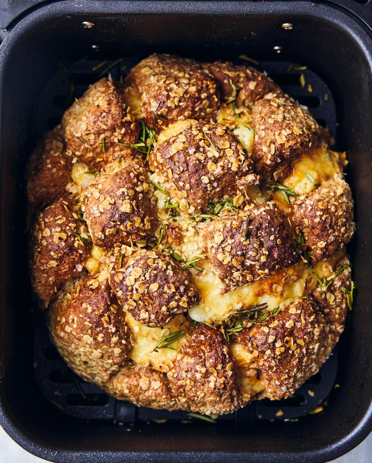 Neues Kochbuch: Sodabrot mit Kräutern & Käse Für 8–10 Personen 250 g Weizenvollkornmehl 200g Weizenmehl Type 405, plus mehr zum Verarbeiten 50g Haferflocken, plus mehr zum Bestreuen 1 gehäufter TL Backnatron 4 Zweige Rosmarin 1 großes Ei 300ml Buttermilch oder 300g Joghurt 100g Red Leicester oder Cheddar Vorbereitung 16 Minuten Garzeit 30 Minuten 1 Schublade In einer großen Schüssel beide Mehle, die Haferflocken, das Backnatron und 1 gestrichenen TL Meersalz vermengen. Den Rosmarin abzupfen, den größten Teil fein hacken und unter das Mehl mischen, den Rest beiseitelegen.In der Mitte eine Mulde in das Mehl drücken. Das Ei hineinschlagen, die Buttermilch zugießen und mit einer Gabel gut verrühren. Nach und nach das Mehl vom Rand einarbeiten und alles mit sauberen, leicht bemehlten Händen zu einem Teig verkneten.Den Käse in Würfel schneiden und unter den Teig mengen. Den Teig zu einem Kloß formen und mit eingeölten Händen zu einem runden, etwa 3 cm dicken Fladen ausbreiten. Einige Extrahaferflocken und etwas Meersalz über den Teigfladen streuen und sanft hineindrücken. Den Teig kreuzweise tief einschneiden, vorsichtig in der Airfryer-Schublade platzieren und 20 Minuten bei 180 °C backen.Den restlichen Rosmarin mit 1 TL Olivenöl einreiben, über das Brot streuen und weitere 10 Minuten bei 180°C backen, bis sich eine feste, goldbraune Kruste gebildet hat und das Brot hohl klingt, wenn man gegen den Boden klopft.Das Sodabrot auf einem Gitter abkühlen lassen und warm servieren. Sodabrot mit Kräutern & Käse Für 8–10 Personen 250 g Weizenvollkornmehl 200g Weizenmehl Type 405, plus mehr zum Verarbeiten 50g Haferflocken, plus mehr zum Bestreuen 1 gehäufter TL Backnatron 4 Zweige Rosmarin 1 großes Ei 300ml Buttermilch oder 300g Joghurt 100g Red Leicester oder Cheddar Vorbereitung 16 Minuten Garzeit 30 Minuten 1 Schublade In einer großen Schüssel beide Mehle, die Haferflocken, das Backnatron und 1 gestrichenen TL Meersalz vermengen. Den Rosmarin abzupfen, den größten Teil fein hacken und unter das Mehl mischen, den Rest beiseitelegen.In der Mitte eine Mulde in das Mehl drücken. Das Ei hineinschlagen, die Buttermilch zugießen und mit einer Gabel gut verrühren. Nach und nach das Mehl vom Rand einarbeiten und alles mit sauberen, leicht bemehlten Händen zu einem Teig verkneten.Den Käse in Würfel schneiden und unter den Teig mengen. Den Teig zu einem Kloß formen und mit eingeölten Händen zu einem runden, etwa 3 cm dicken Fladen ausbreiten. Einige Extrahaferflocken und etwas Meersalz über den Teigfladen streuen und sanft hineindrücken. Den Teig kreuzweise tief einschneiden, vorsichtig in der Airfryer-Schublade platzieren und 20 Minuten bei 180 °C backen.Den restlichen Rosmarin mit 1 TL Olivenöl einreiben, über das Brot streuen und weitere 10 Minuten bei 180°C backen, bis sich eine feste, goldbraune Kruste gebildet hat und das Brot hohl klingt, wenn man gegen den Boden klopft.Das Sodabrot auf einem Gitter abkühlen lassen und warm servieren.