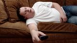 Mann schläft mit Fernbedienung auf Sofa