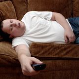 Mann schläft mit Fernbedienung auf Sofa