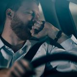 Mann schläft am Steuer seines Autos ein