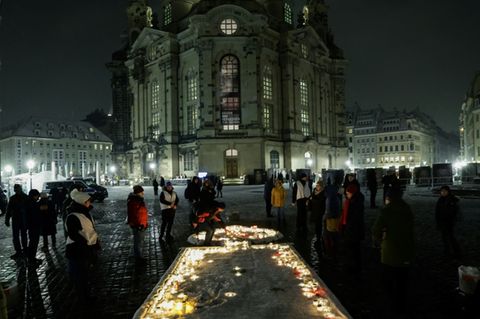 Menschen entzünden Kerzen vor der Frauenkirche