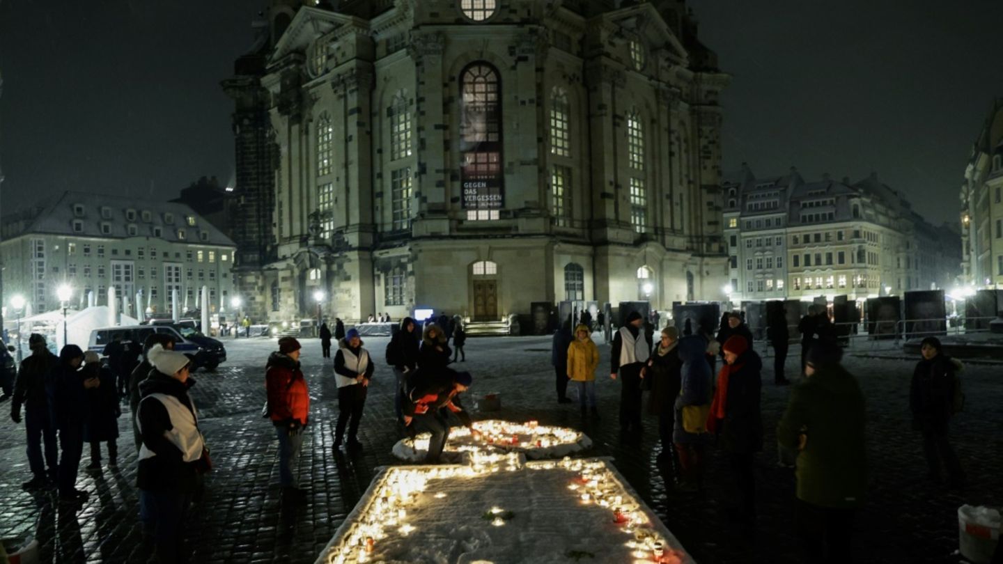 Menschen entzünden Kerzen vor der Frauenkirche