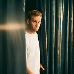 Psychologe Leon Windscheid tritt aus einem Vorhang hervor