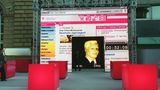 Die virtuelle Figur Robert von T-Online im Bildschirm neben dem ehemaligen Vorstandsvorsitzenden Wolfgang Keuntje (r.)