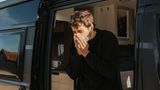 Körper-Fakten: Ein junger Mann niest in sein Taschentuch