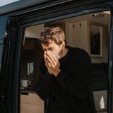 Körper-Fakten: Ein junger Mann niest in sein Taschentuch