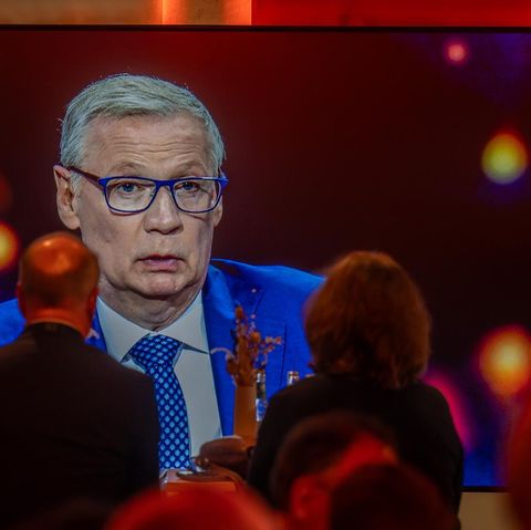 Günther Jauch ist beim TV-Quadrell auf einem Bildschirm zu sehen. Er trägt Anzug, Krawatte und Brille