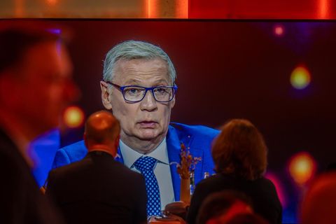 Günther Jauch ist beim TV-Quadrell auf einem Bildschirm zu sehen. Er trägt Anzug, Krawatte und Brille