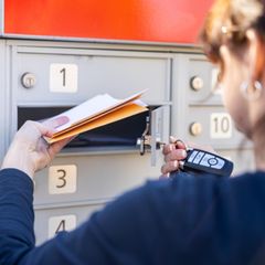 Eine Frau holt Post aus dem Briefkasten