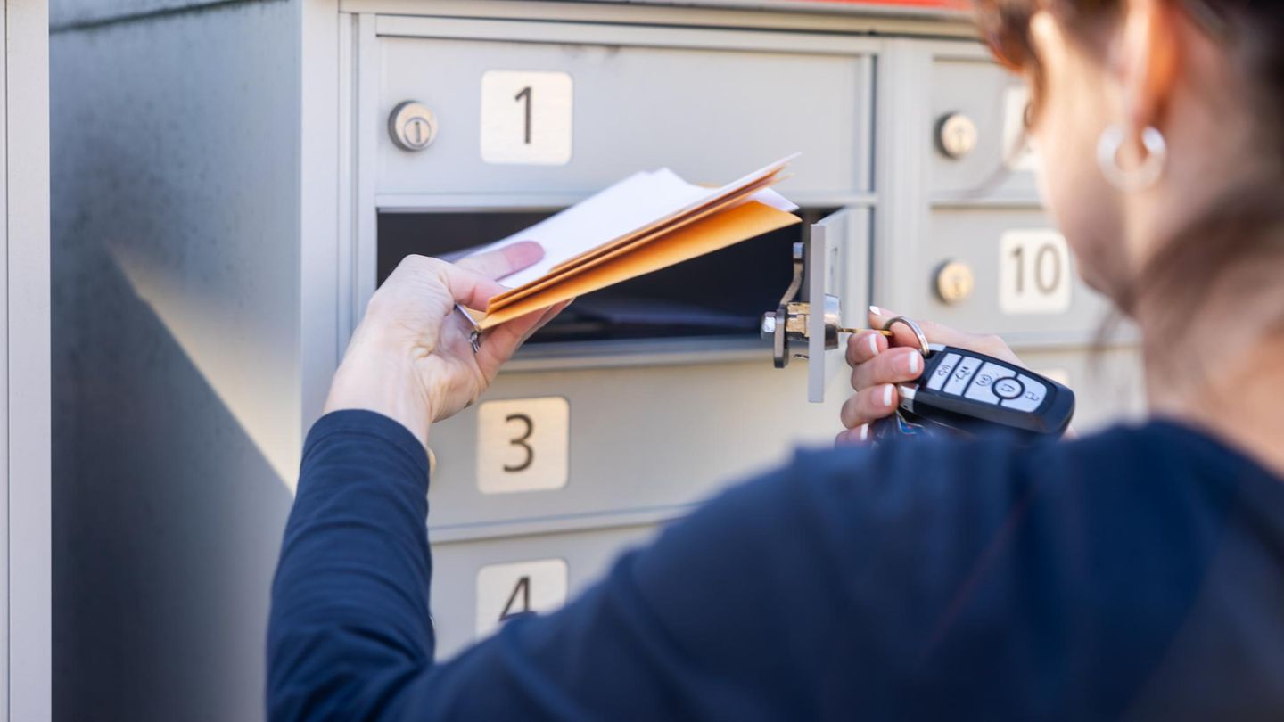Eine Frau holt Post aus dem Briefkasten