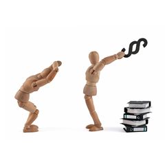 Eine Holzpuppe droht, einer anderen Holzpuppe mit einem Paragraphenzeichen auf den Kopf zu schlagen