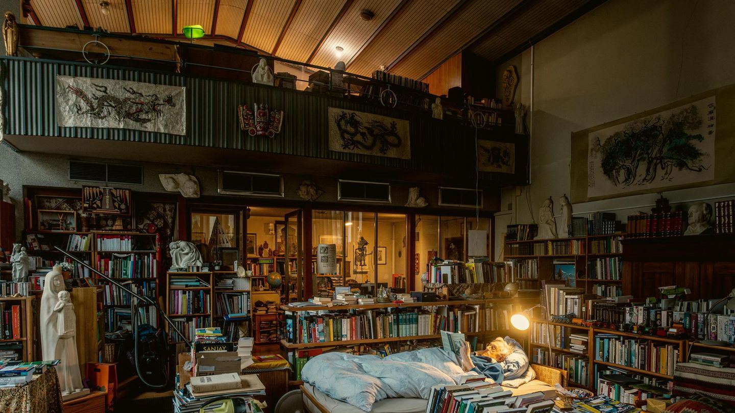 Ein Ehepaar und 40.000 Bücher Ein Mann liest im Bett inmitten einer Bücherlandschaft.