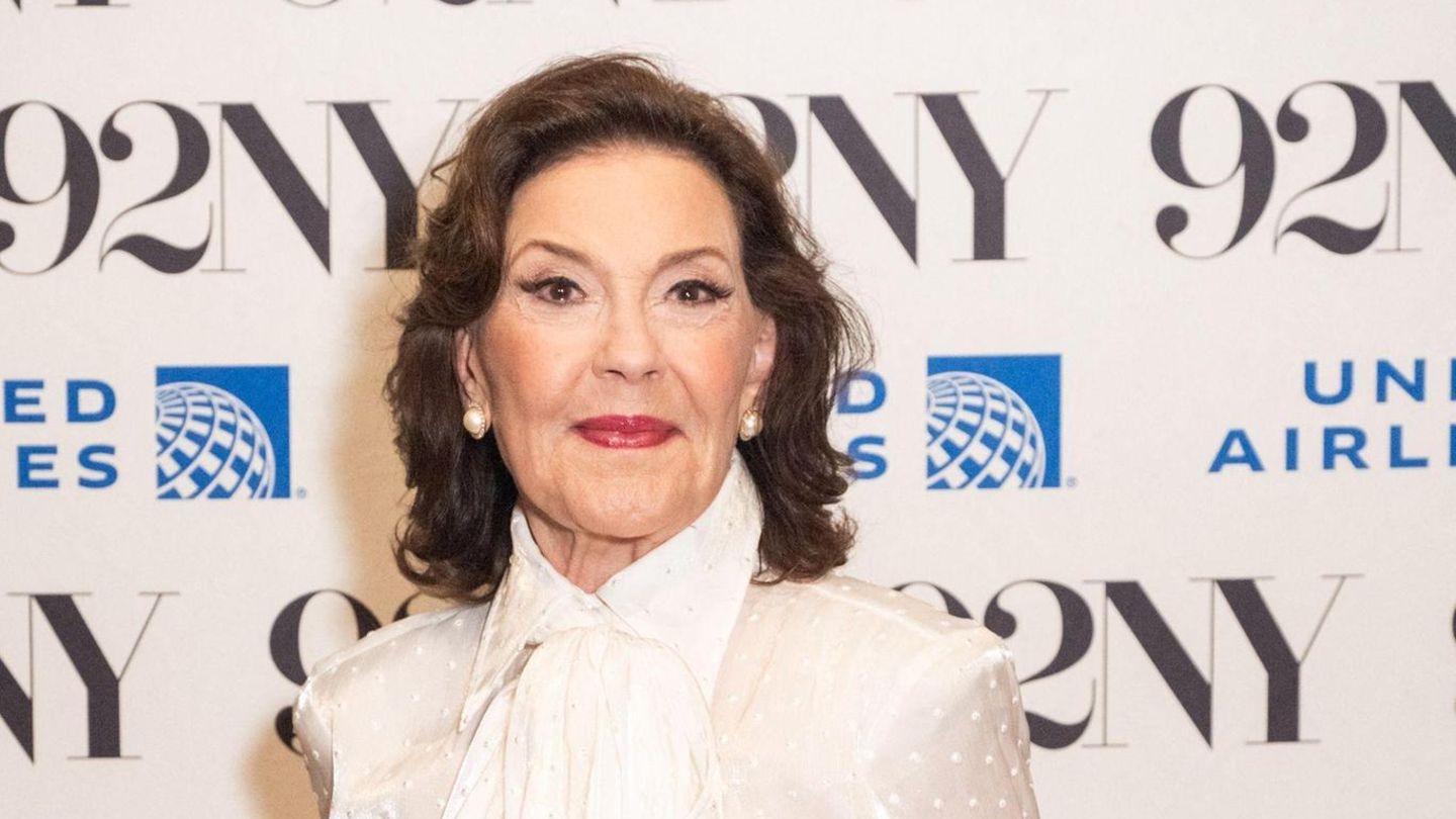 Kelly Bishop im Portrait. Sie schulterlange braune Haare und trägt eine weiße Bluse