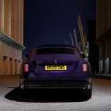 Ein lilaner Rolls-Royce beim Fahren auf der Straße von hinten fotografiert